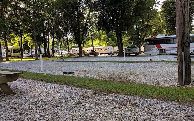 A long, level gravel pull-through pad with hookup posts and a picnic table